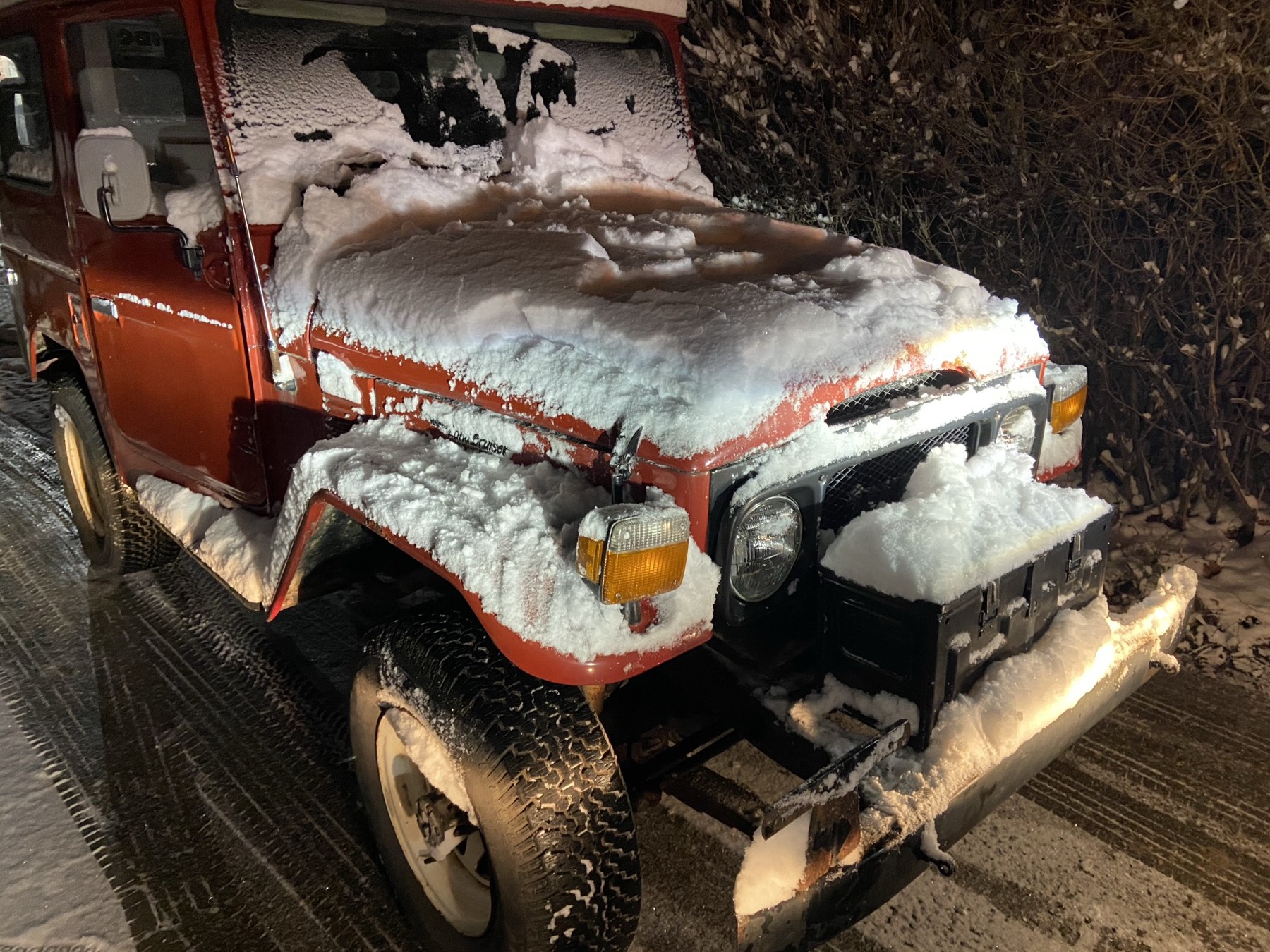 Orange Toyota BJ40 Land Cruiser buried in fresh snow at night