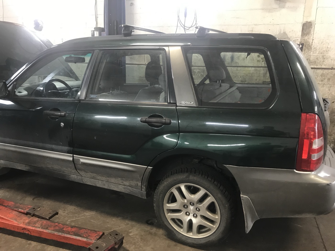Green 2004 Forester XS on a lift in the shop