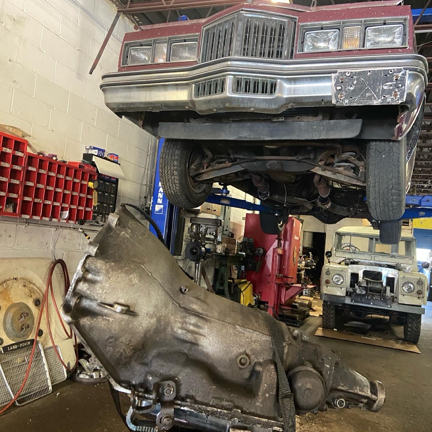 1978 Pontiac Grand Prix on a lift with its transmission removed on the shop floor