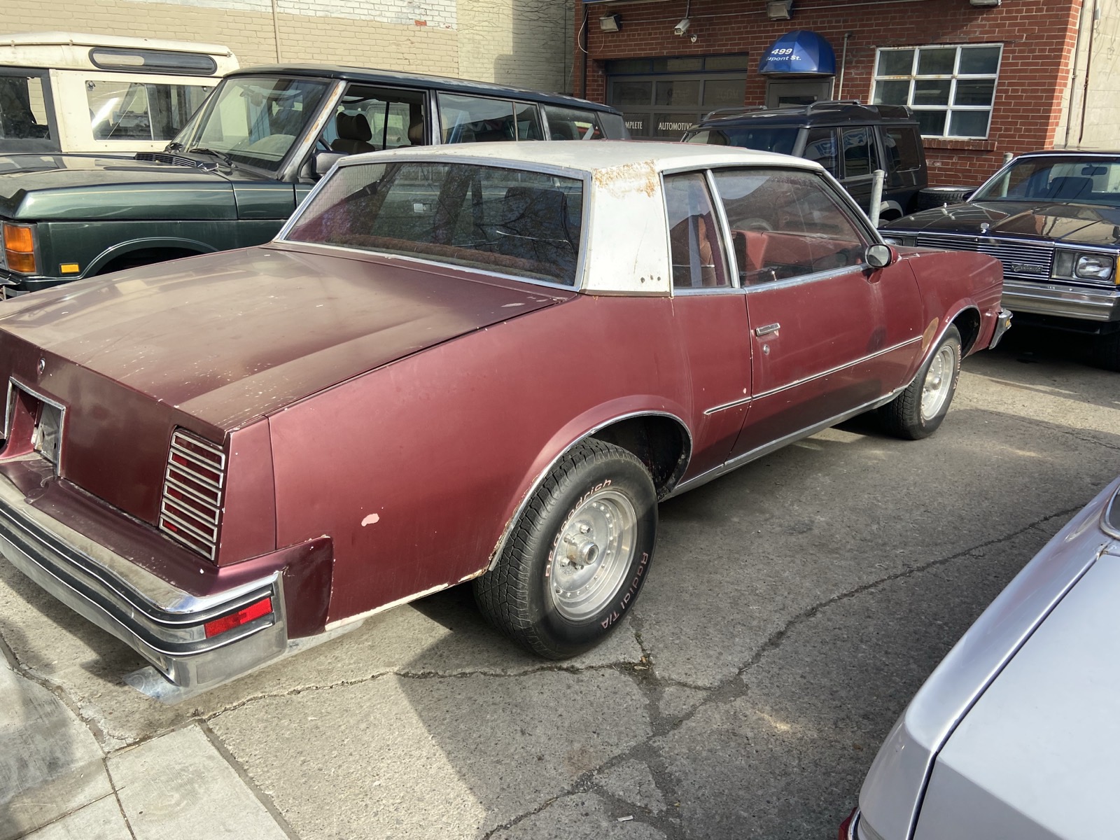 Rear three-quarter view of the burgundy Grand Prix on the street