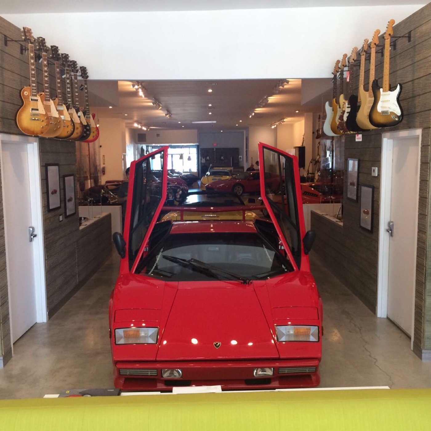Red Lamborghini Countach with scissor doors open in a guitar showroom
