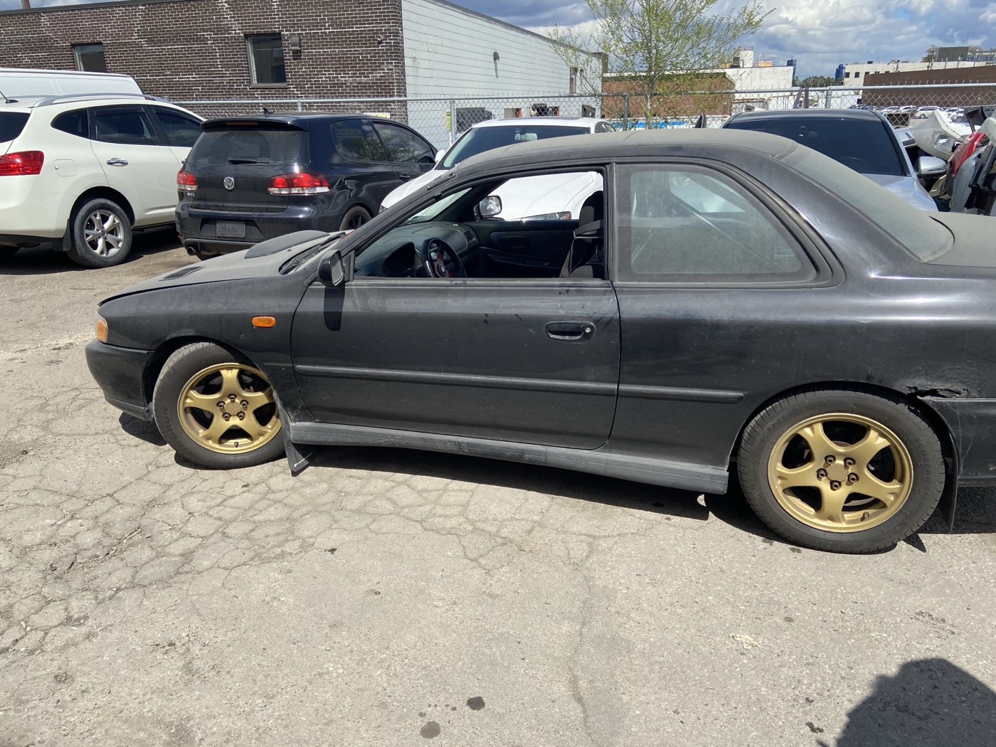 Black GC8 2.5RS coupe with the door open in a parking lot