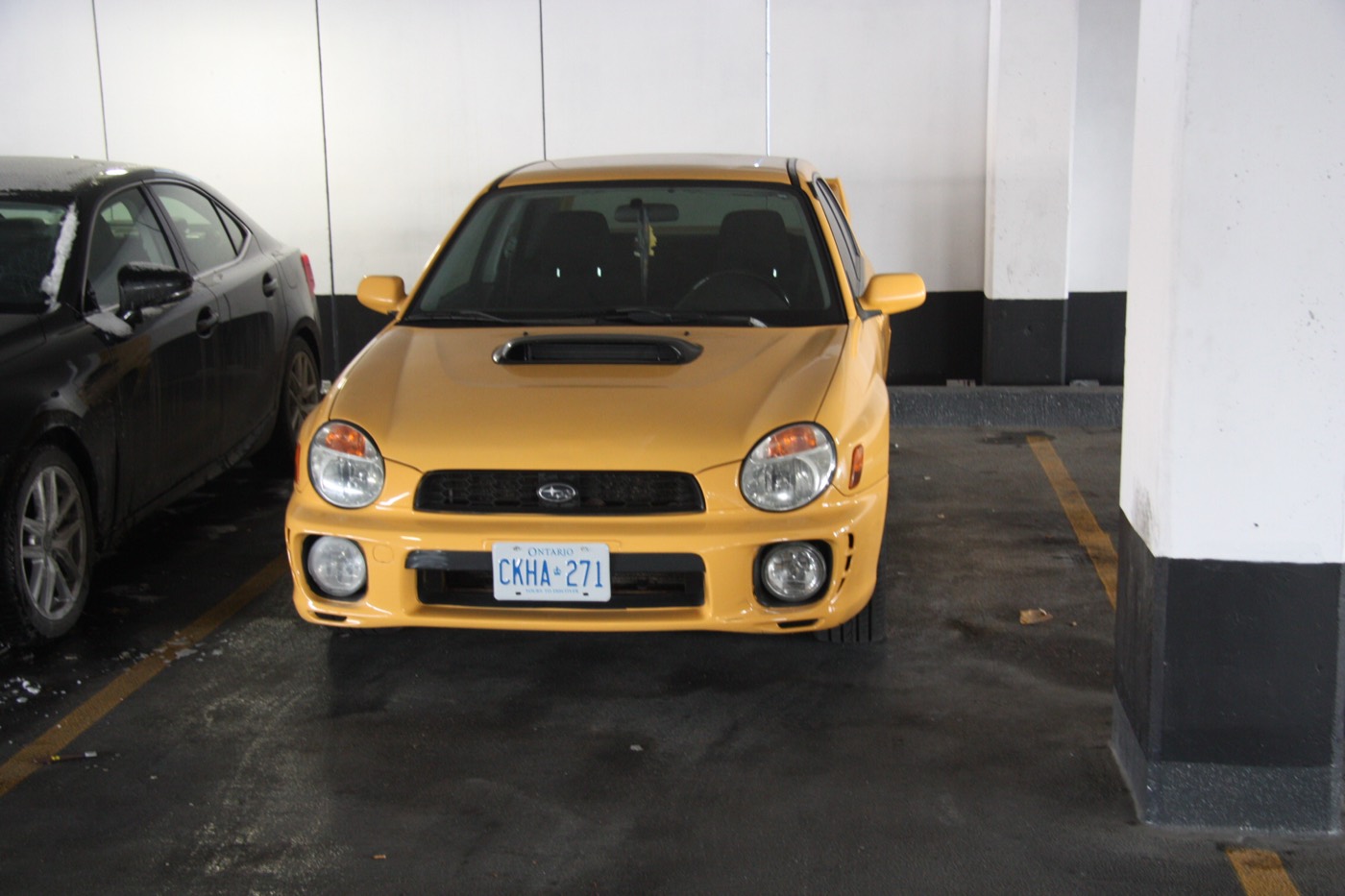 Yellow Subaru parked in an underground garage