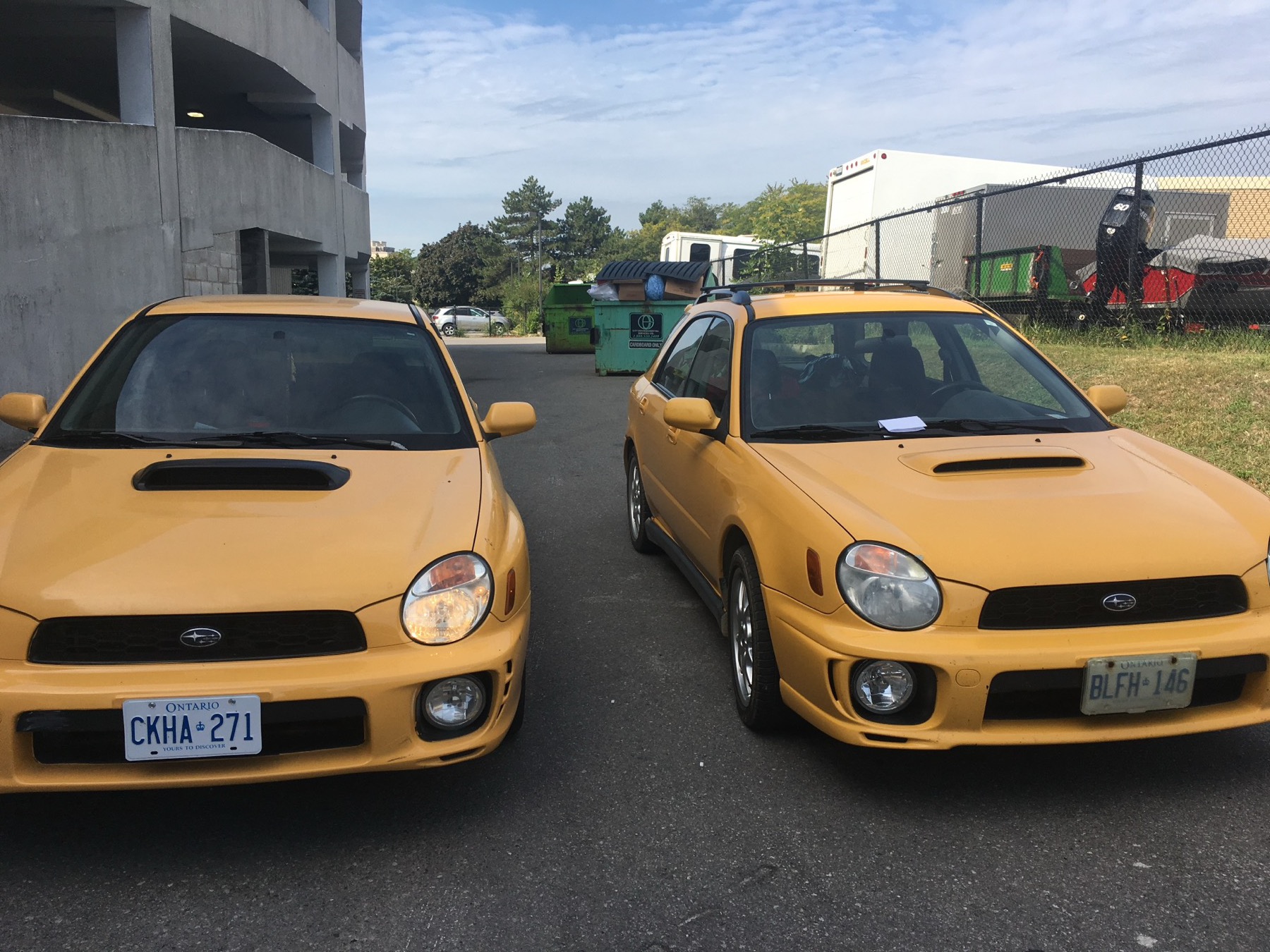 Two Sonic Yellow 2003 Subaru WRXs, a sedan and a wagon, parked side by side