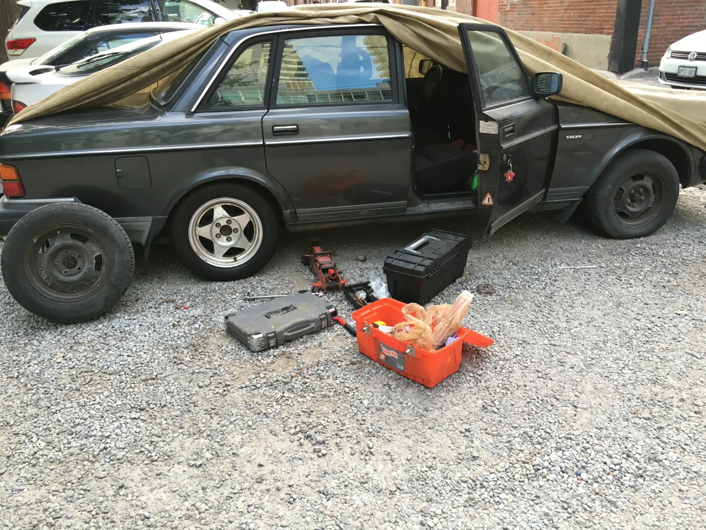 Grey Volvo 240 with parts laid out beside it